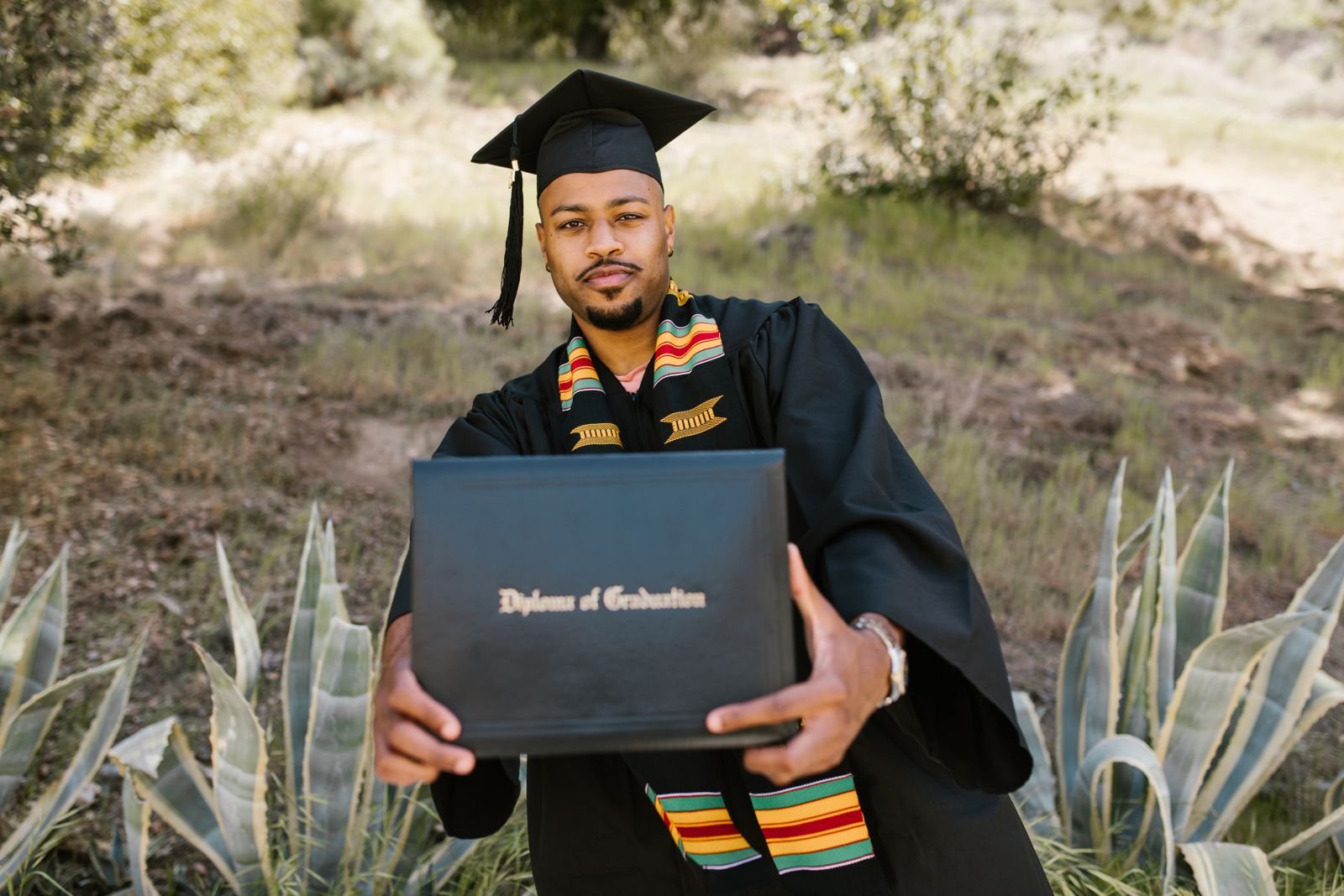Graduates holding rolled diplomas tied with ribbon